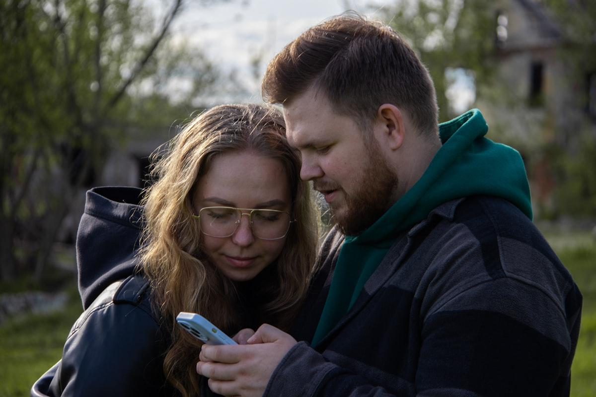 Dwie osoby wspólnie przeglądające telefon na świeżym powietrzu